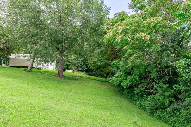 a view of a white house with a big yard and large trees