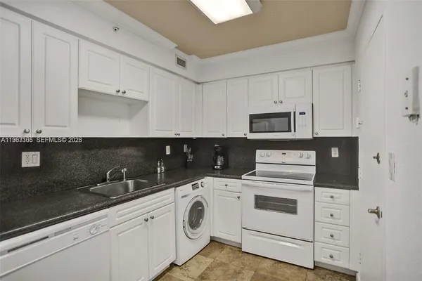 a kitchen with white cabinets and white appliances