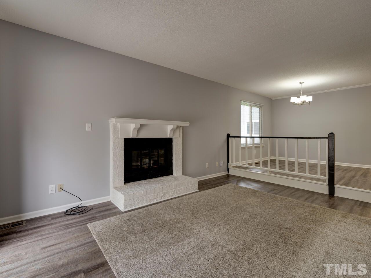 5857 Branchwood Road Raleigh, NC 27609 - Photo 11 of 42 a view of an empty room with wooden floor and a fireplace