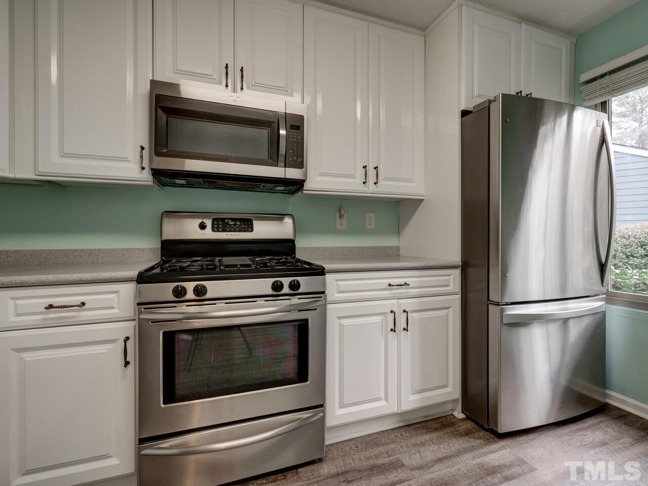 5857 Branchwood Road Raleigh, NC 27609 - Photo 16 of 42 a kitchen with stainless steel appliances white cabinets white stove a microwave and a refrigerator