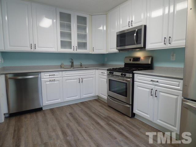 5857 Branchwood Road Raleigh, NC 27609 - Photo 4 of 42 a kitchen with granite countertop white cabinets and stainless steel appliances