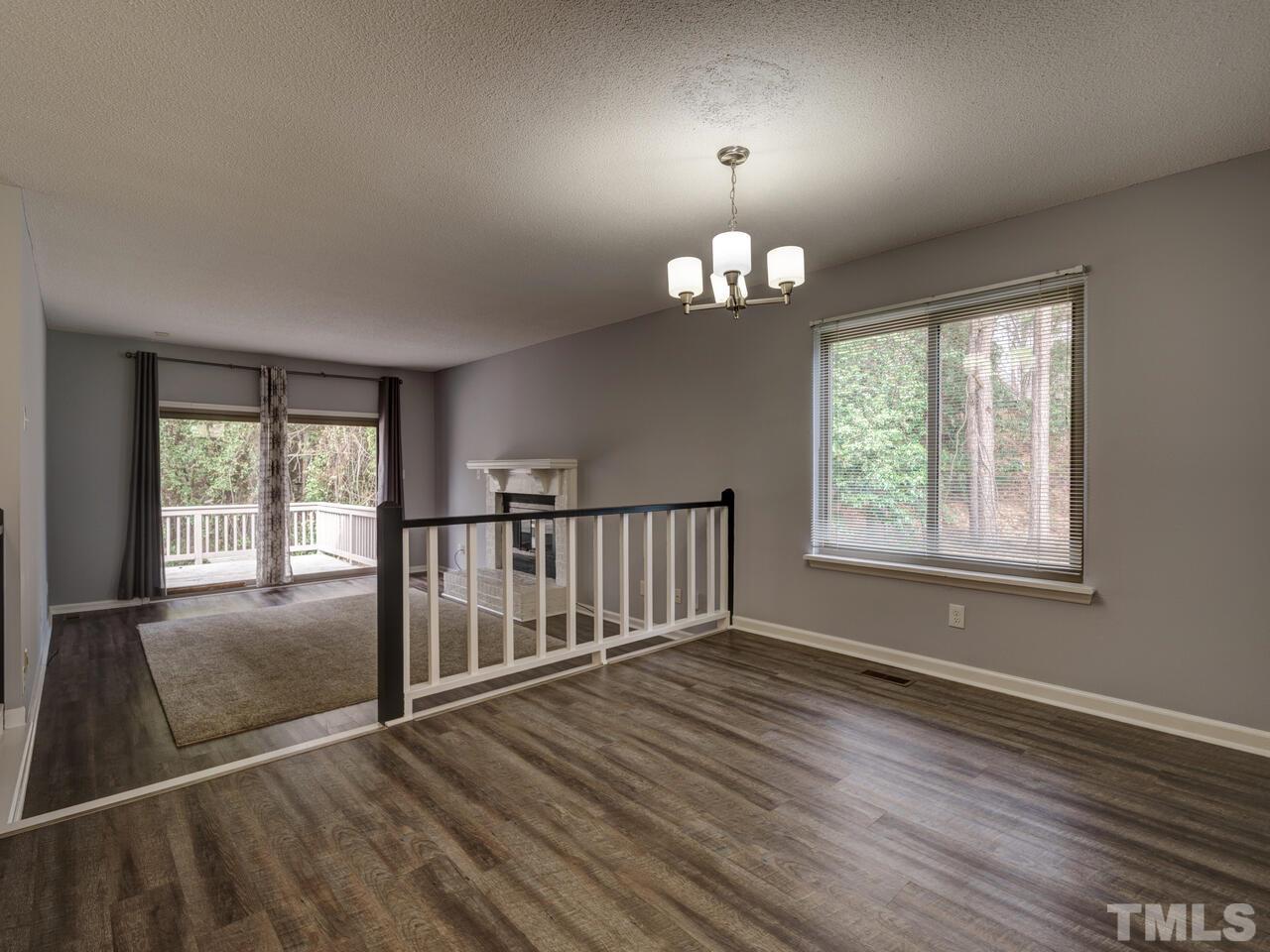 5857 Branchwood Road Raleigh, NC 27609 - Photo 7 of 42 an empty room with wooden floor chandelier and windows