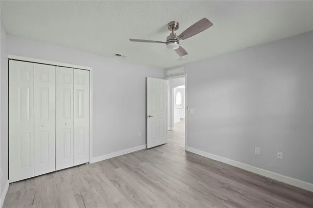 an empty room with wooden floor ceiling fan and windows