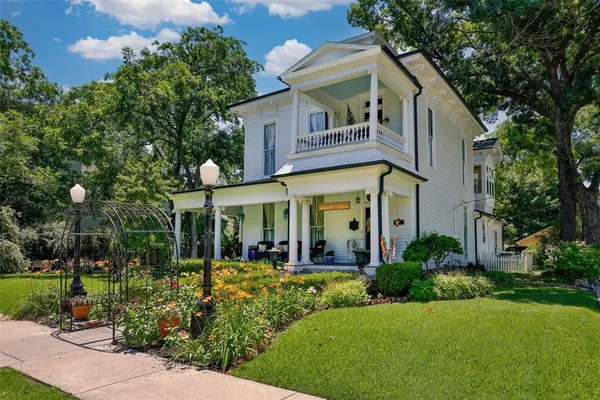 a view of a white house with a yard and potted plants