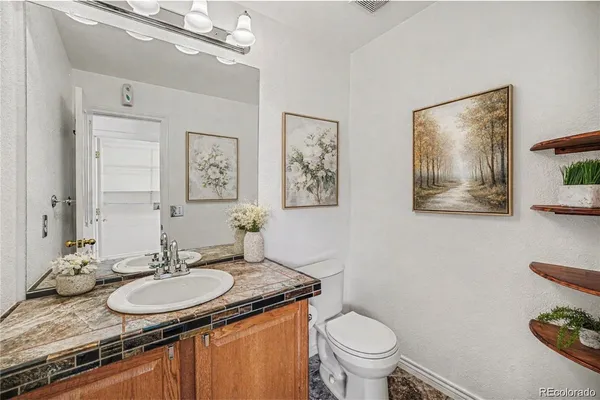 a bathroom with a granite countertop toilet a sink and a mirror