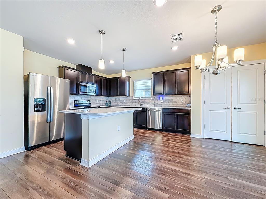 9324 Rally Spring Loop Wesley Chapel, FL 33545 - Photo 13 of 57 a kitchen with kitchen island granite countertop stainless steel appliances cabinets a sink and a wooden floor