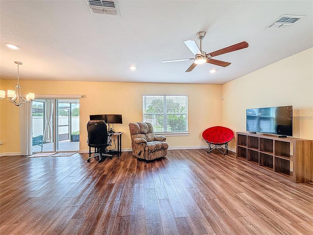 9324 Rally Spring Loop Wesley Chapel, FL 33545 - Photo 17 of 57 a living room with furniture a flat screen tv and a floor to ceiling window