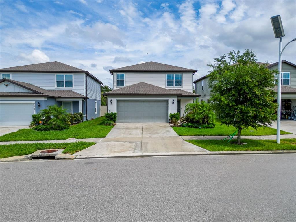 9324 Rally Spring Loop Wesley Chapel, FL 33545 - Photo 2 of 57 a front view of a house with a yard and a garage