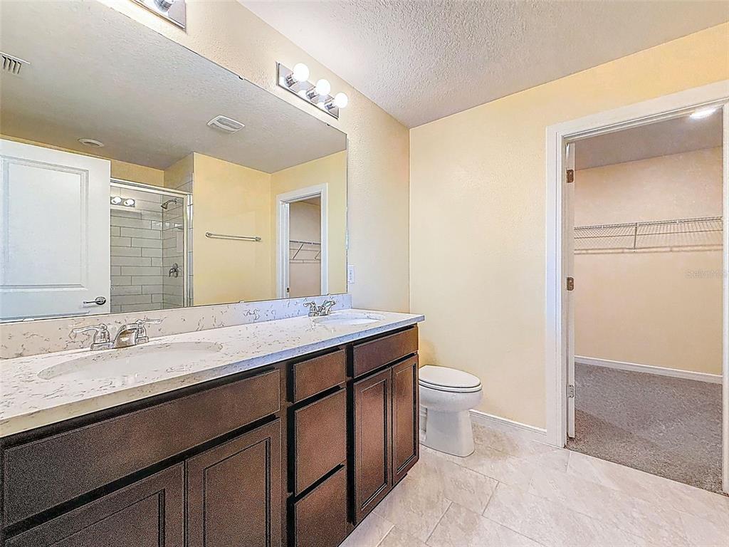 9324 Rally Spring Loop Wesley Chapel, FL 33545 - Photo 29 of 57 a bathroom with a double vanity sink toilet and a mirror