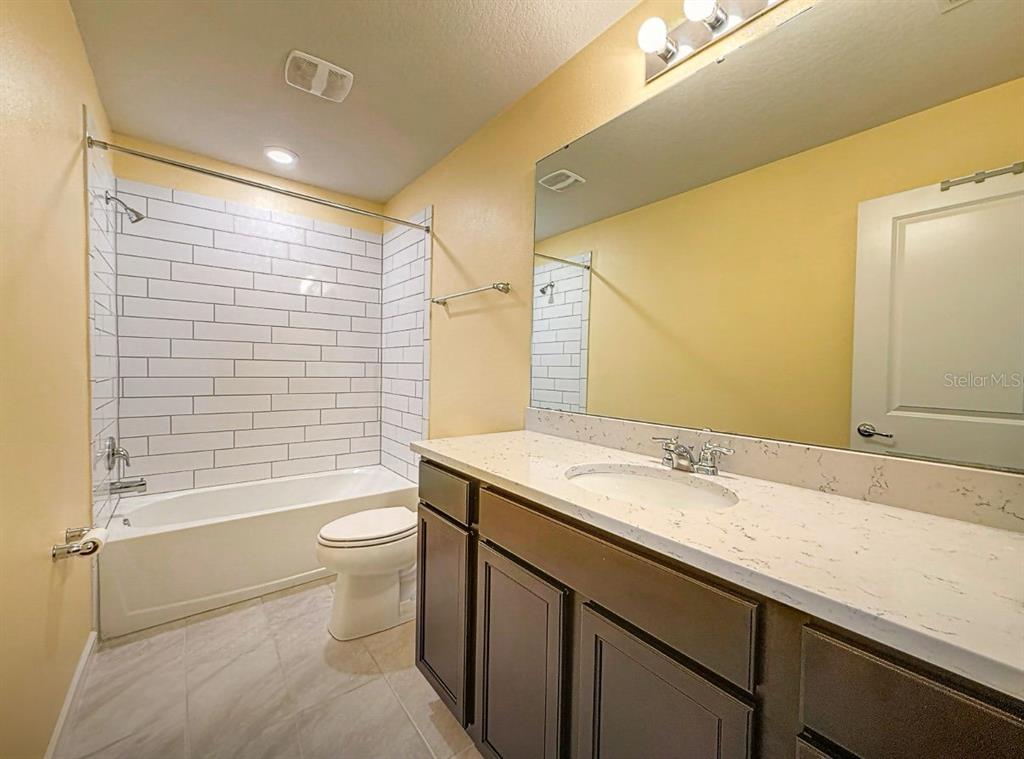 9324 Rally Spring Loop Wesley Chapel, FL 33545 - Photo 10 of 57 a bathroom with a sink a toilet a mirror and shower