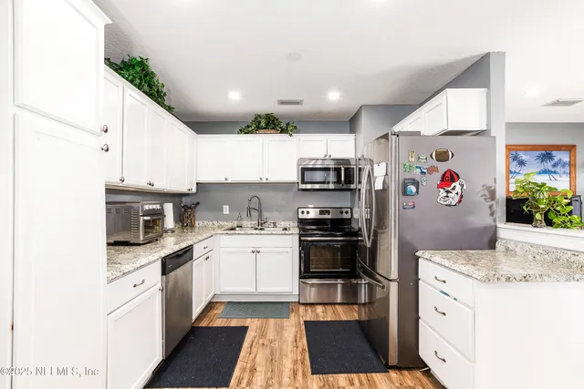 a kitchen with stainless steel appliances granite countertop a refrigerator and a stove top oven