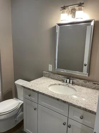 a bathroom with a granite countertop sink a toilet and mirror