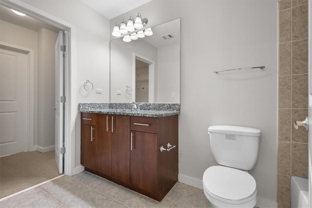 250 Pharr Road Northeast, Unit 309 Atlanta, GA 30305 - Photo 11 of 37 a bathroom with a granite countertop toilet sink and mirror