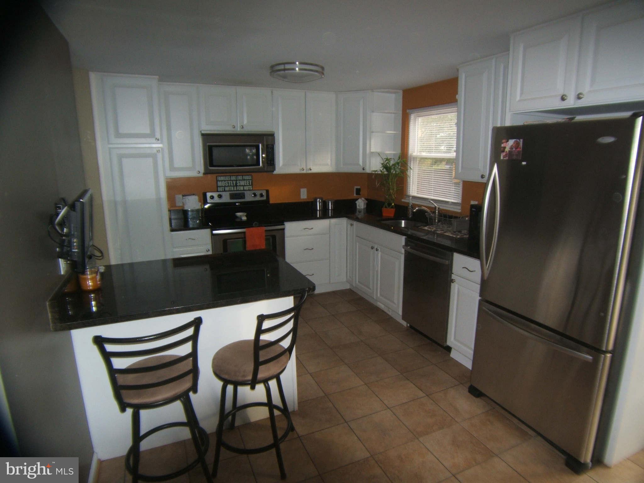 19113 Staleybridge Road Germantown, MD 20876 - Photo 7 of 17 a kitchen with a refrigerator and a stove top oven