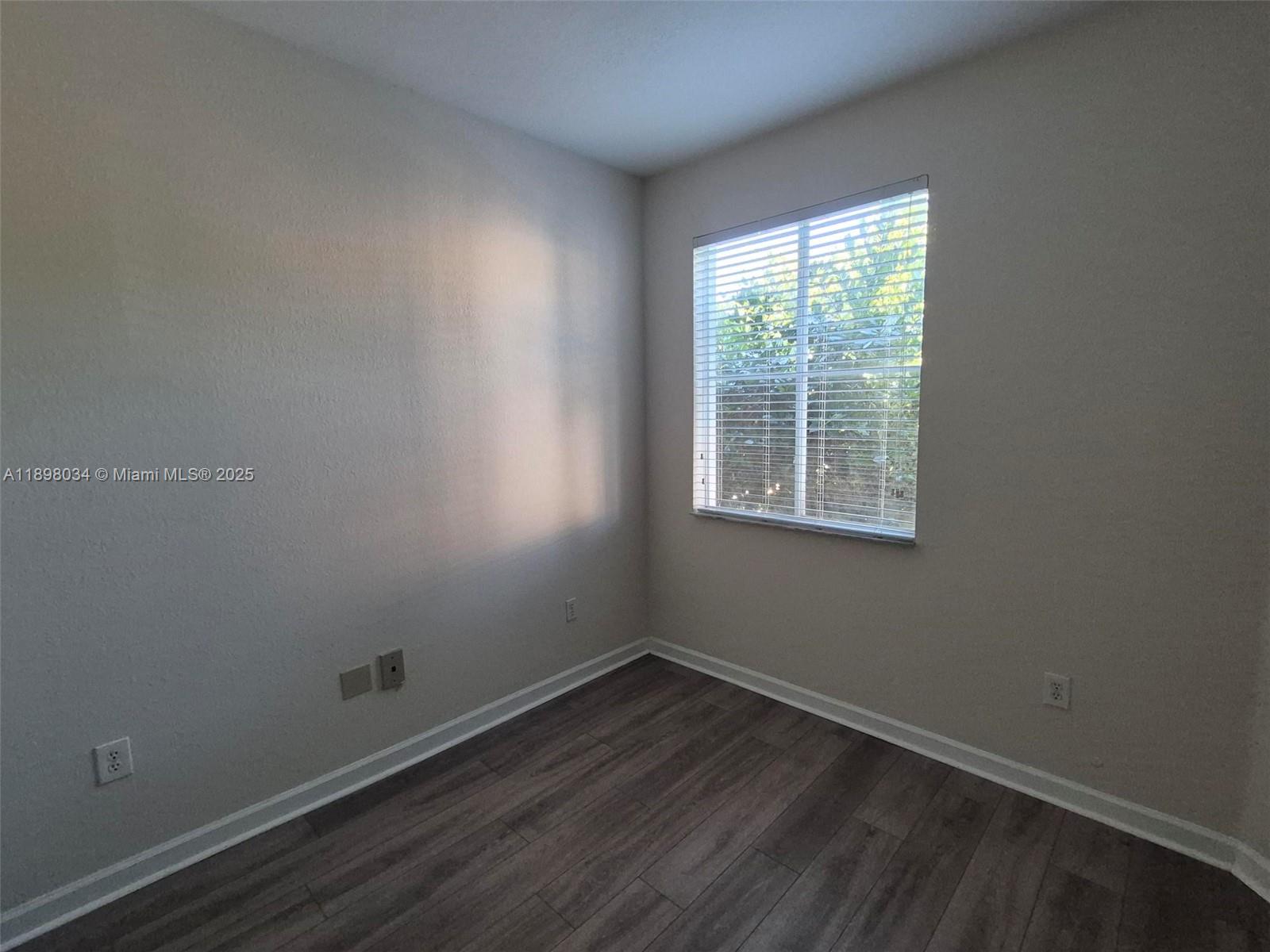 17820 Northwest 73rd Avenue, Unit 2011 Hialeah, FL 33015 - Photo 13 of 16 an empty room with wooden floor and windows