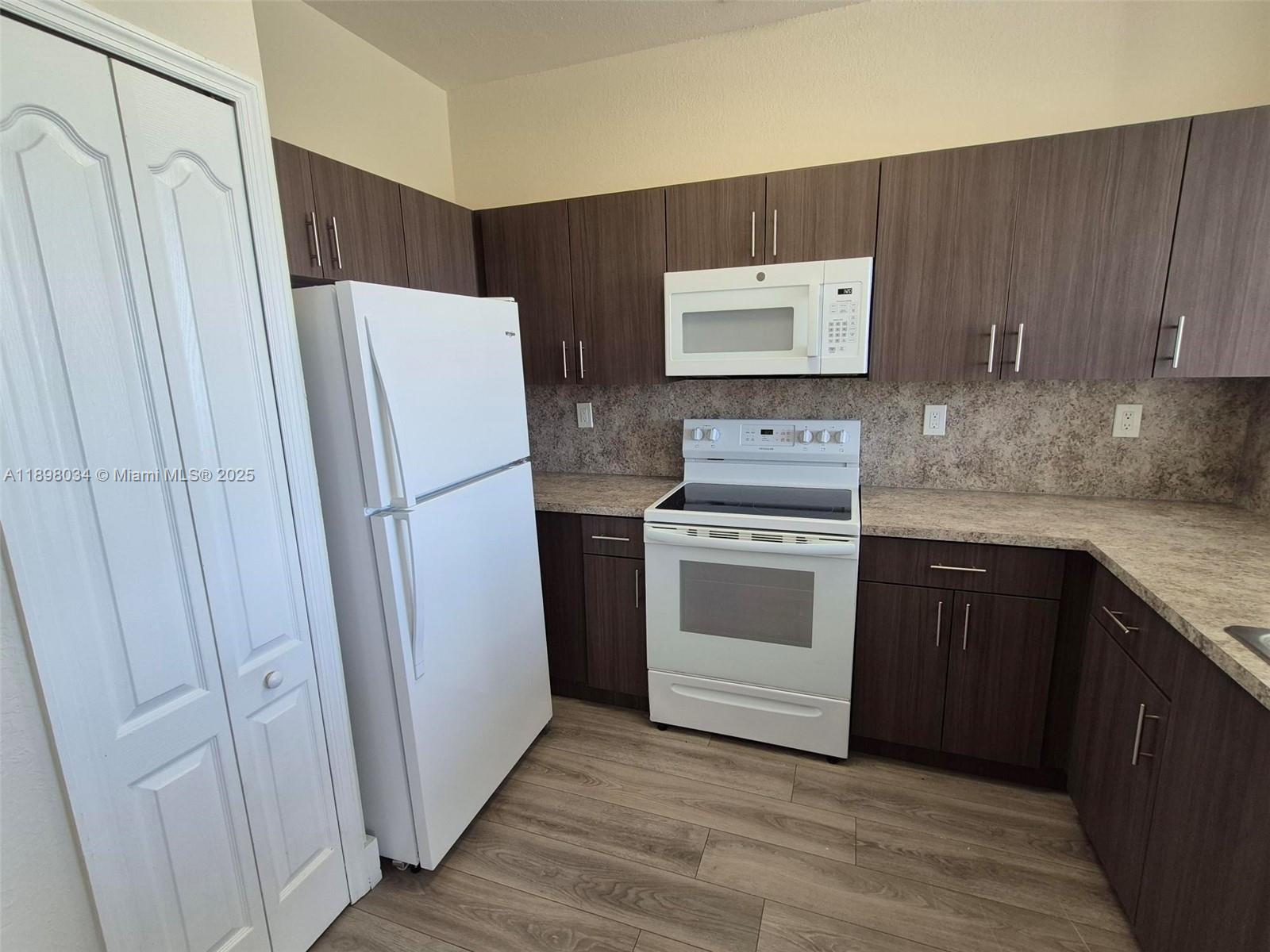 17820 Northwest 73rd Avenue, Unit 2011 Hialeah, FL 33015 - Photo 5 of 16 a kitchen with a stove cabinets and refrigerator