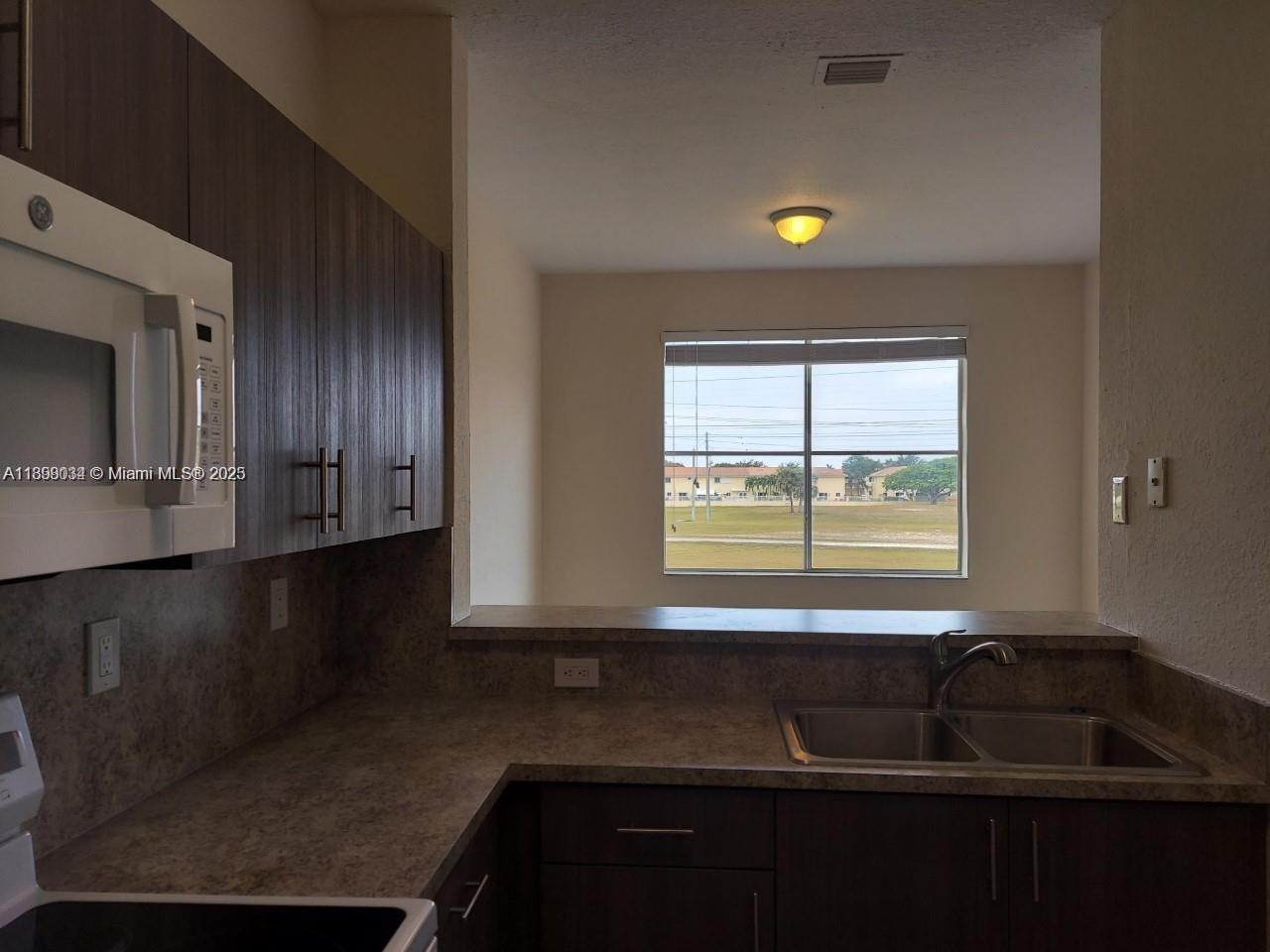 17820 Northwest 73rd Avenue, Unit 2011 Hialeah, FL 33015 - Photo 6 of 16 a kitchen that has a sink cabinets and a window