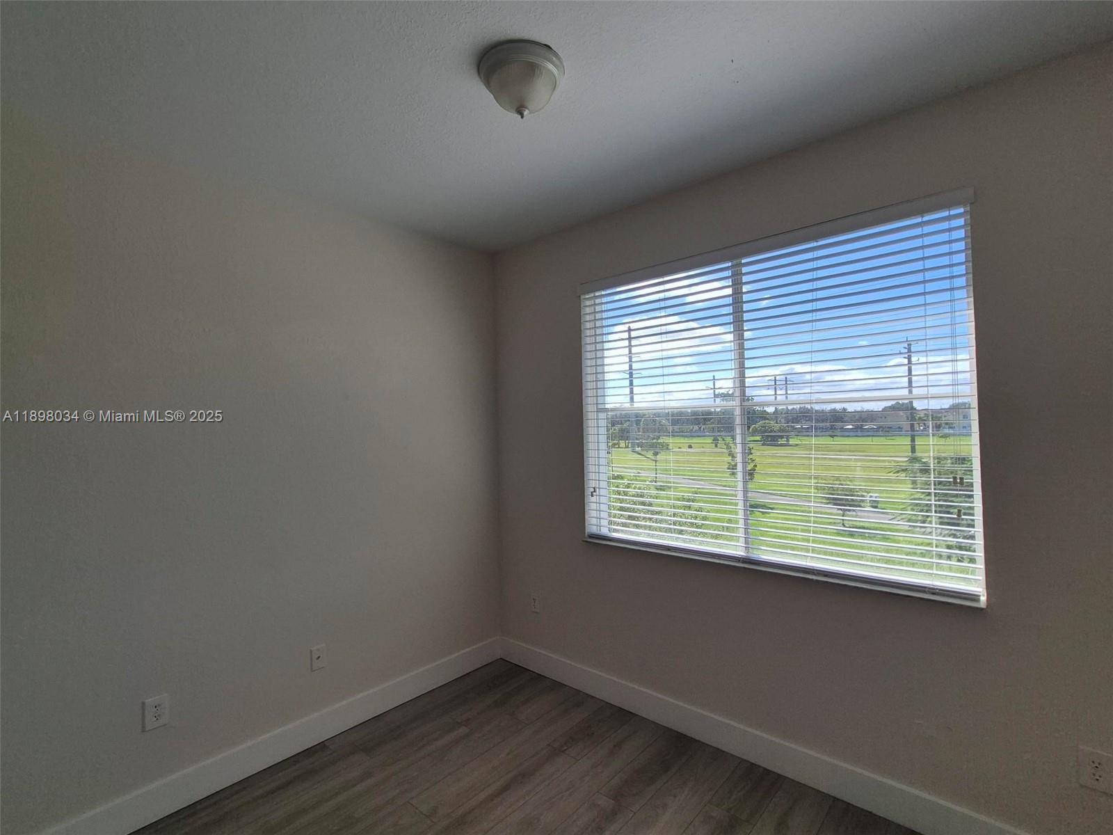 17820 Northwest 73rd Avenue, Unit 2011 Hialeah, FL 33015 - Photo 7 of 16 a view of an empty room with wooden floor and a window