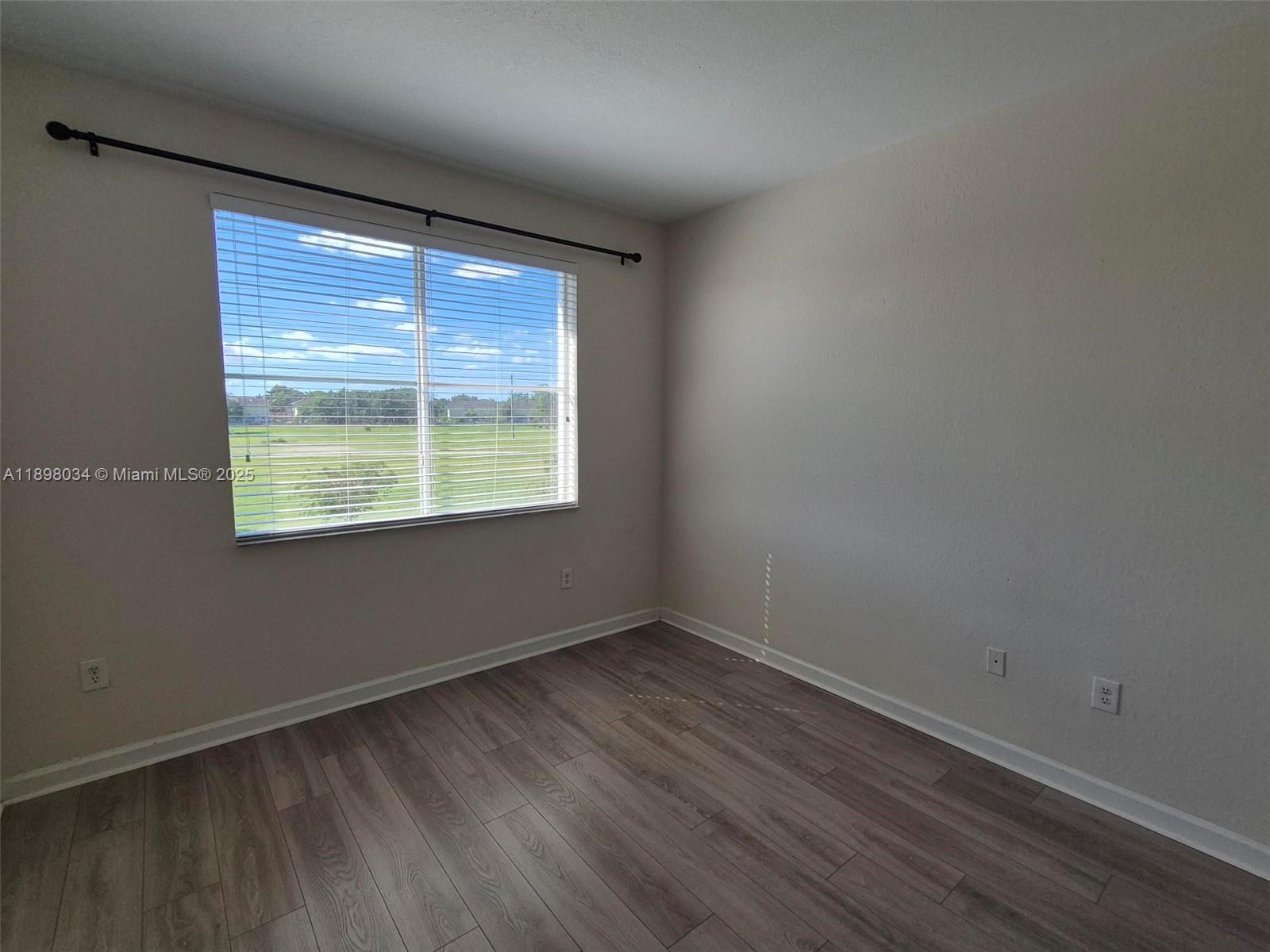 17820 Northwest 73rd Avenue, Unit 2011 Hialeah, FL 33015 - Photo 8 of 16 a view of an empty room with wooden floor and a window