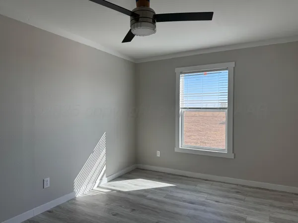 an empty room with wooden floor ceiling fan and windows