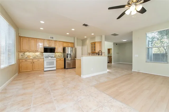 a view of a kitchen with kitchen island wooden floor center island stainless steel appliances and cabinets