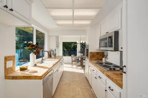 a large white kitchen with a stove and a large window