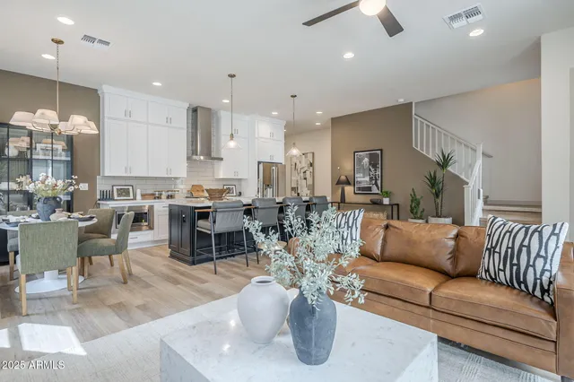 a living room with lots of furniture kitchen view and a chandelier