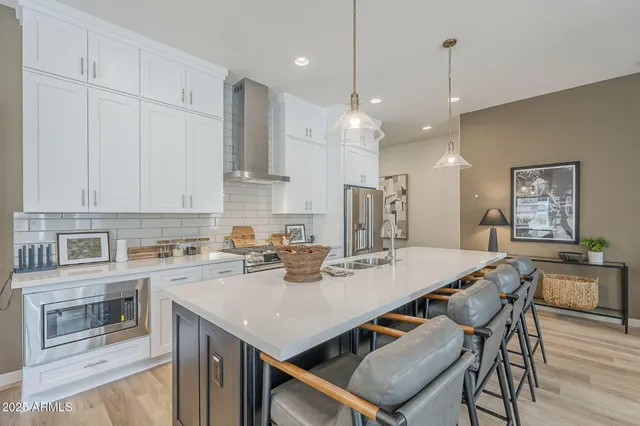 a kitchen with a stove a refrigerator a sink a dining table and chairs with wooden floor