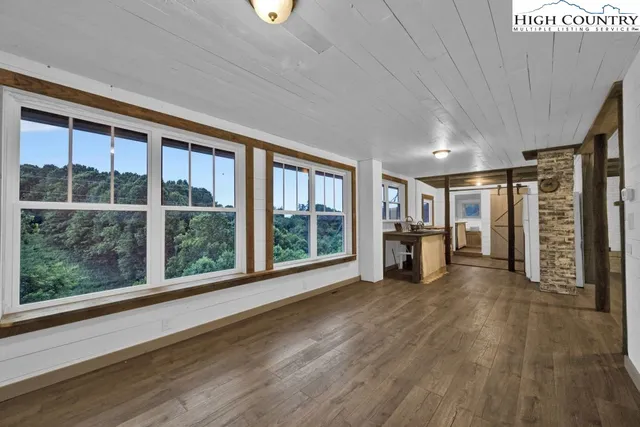 a room with lots of wooden furniture and a glass door shower