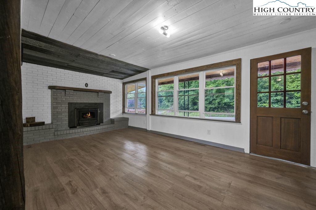 244 Flat Springs Road Elk Park, NC 28622 - Photo 26 of 47 an empty room with wooden floor fireplace and windows