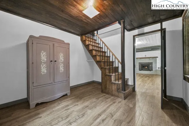 an empty room with wooden floor chandelier and windows
