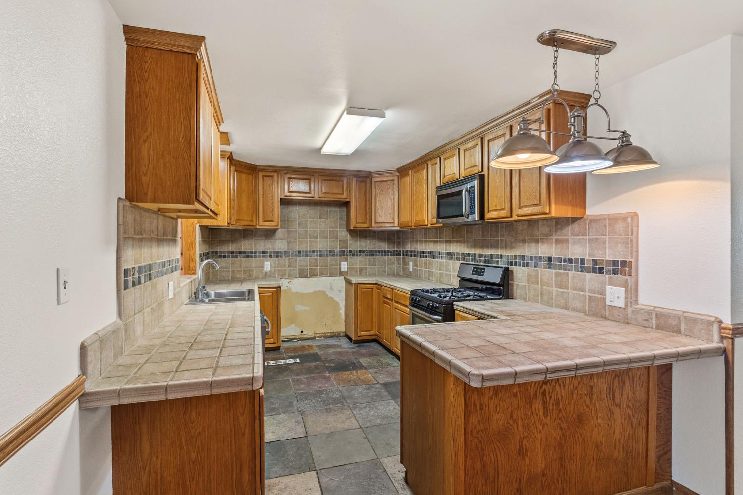 1805 Aloha Way Modesto, CA 95350 - Photo 6 of 24 a kitchen with a stove a sink and a microwave