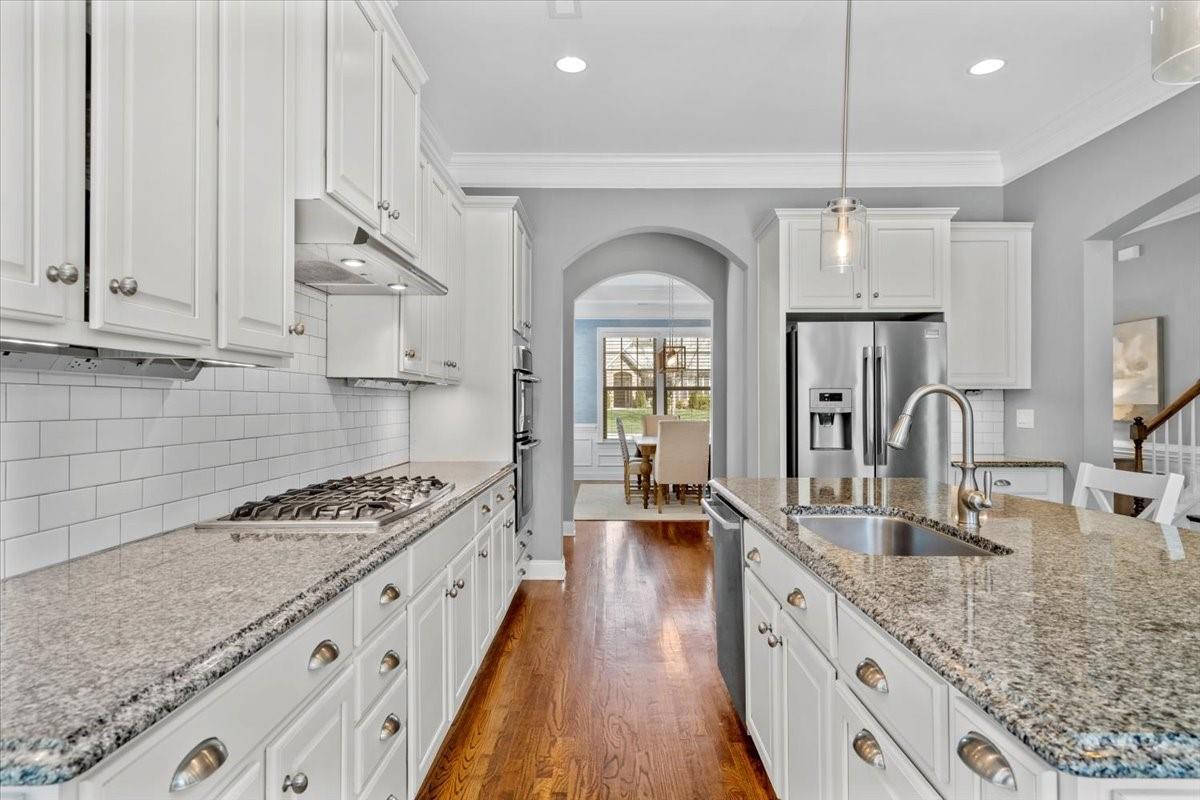 8131 Clems Branch Road Indian Land, SC 29707 - Photo 14 of 47 a kitchen with granite countertop a stove a sink dishwasher and white cabinets with wooden floor