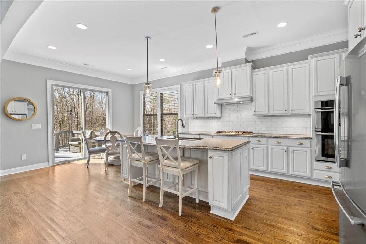 8131 Clems Branch Road Indian Land, SC 29707 - Photo 9 of 47 a kitchen with stainless steel appliances granite countertop a stove top oven a sink dishwasher a dining table and chairs with wooden floor