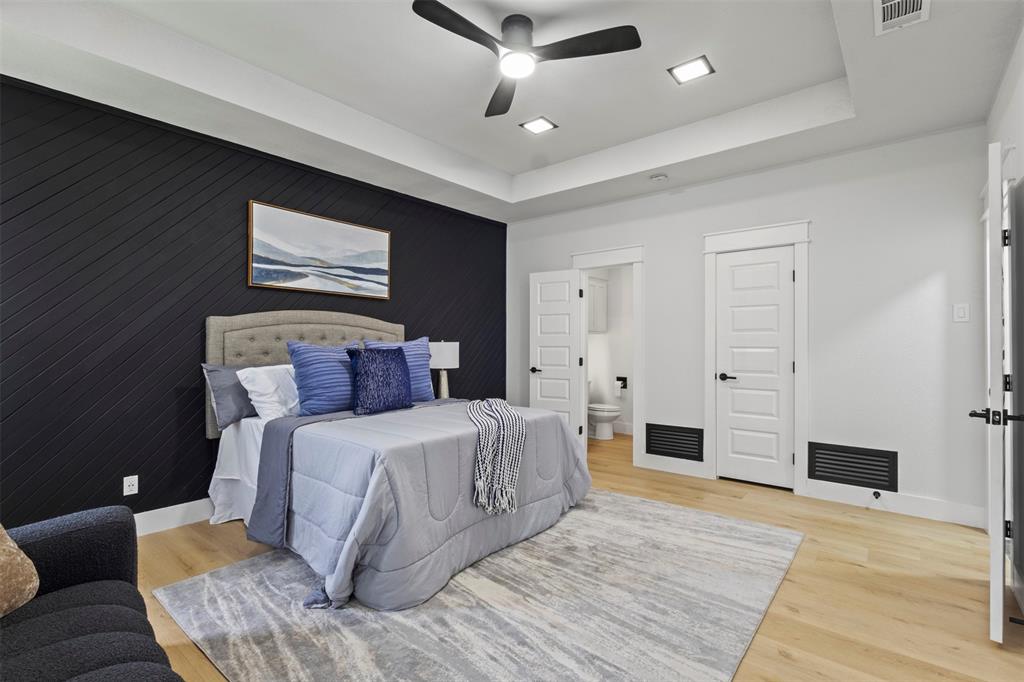 1 Spring Valley Court Richardson, TX 75081 - Photo 12 of 40 Bedroom with a tray ceiling, wooden walls, light wood finished floors, a ceiling fan, and ensuite bathroom