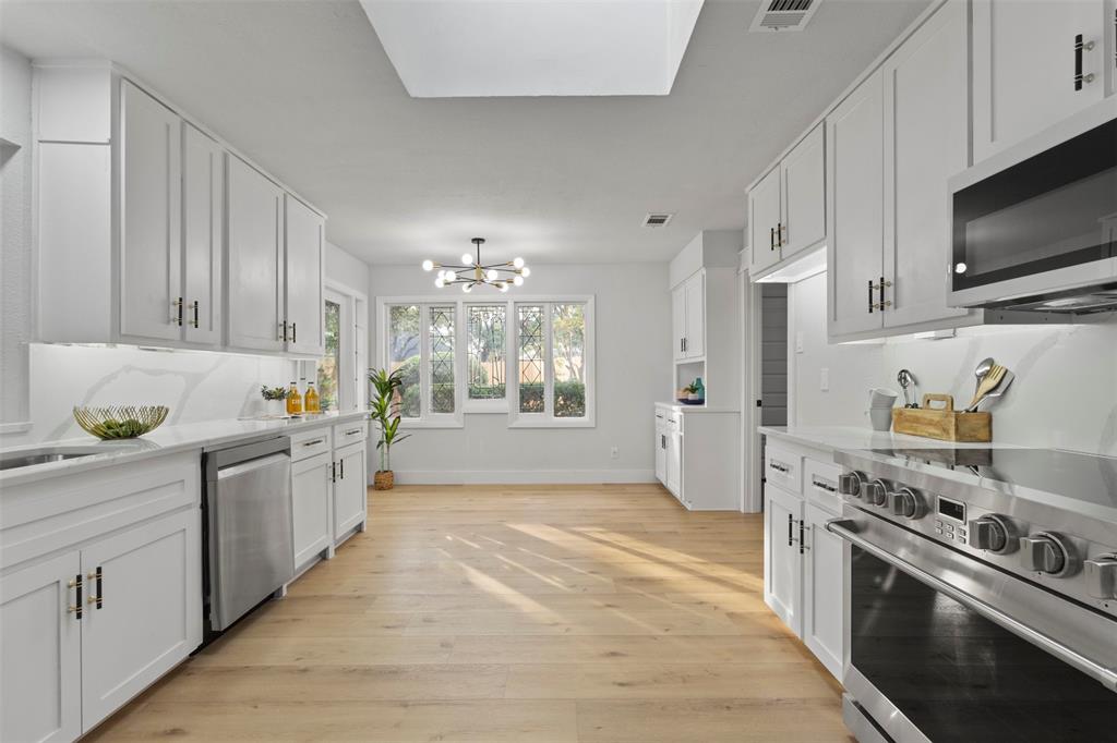 1 Spring Valley Court Richardson, TX 75081 - Photo 17 of 40 Kitchen featuring stainless steel appliances, a chandelier, white cabinets, light wood finished floors, and light stone countertops