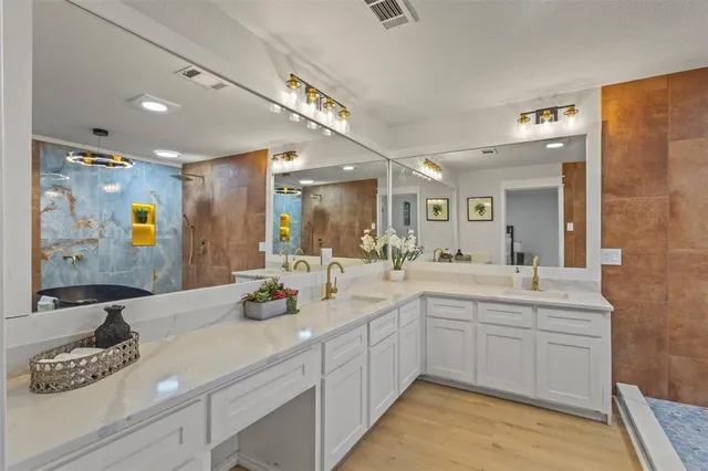 a bathroom with a sink vanity granite tub and a mirror