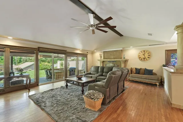 a living room with furniture a ceiling fan and a floor to ceiling window