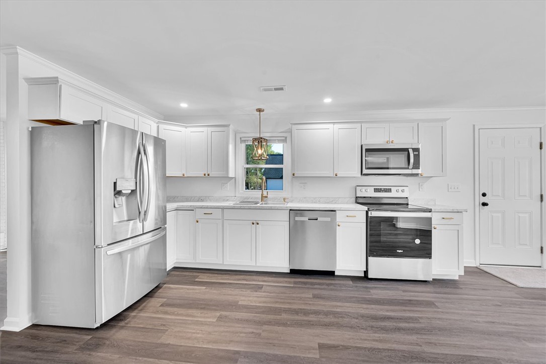 801 Cherokee Road Pelzer, SC 29669 - Photo 17 of 45 This newly renovated kitchen features white cabinetry, sleek stainless steel appliances, and wood flooring.