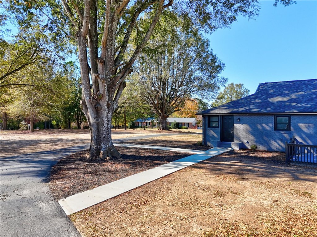 801 Cherokee Road Pelzer, SC 29669 - Photo 40 of 45 This charming home offers ample outdoor space with mature trees and a neatly paved walkway.