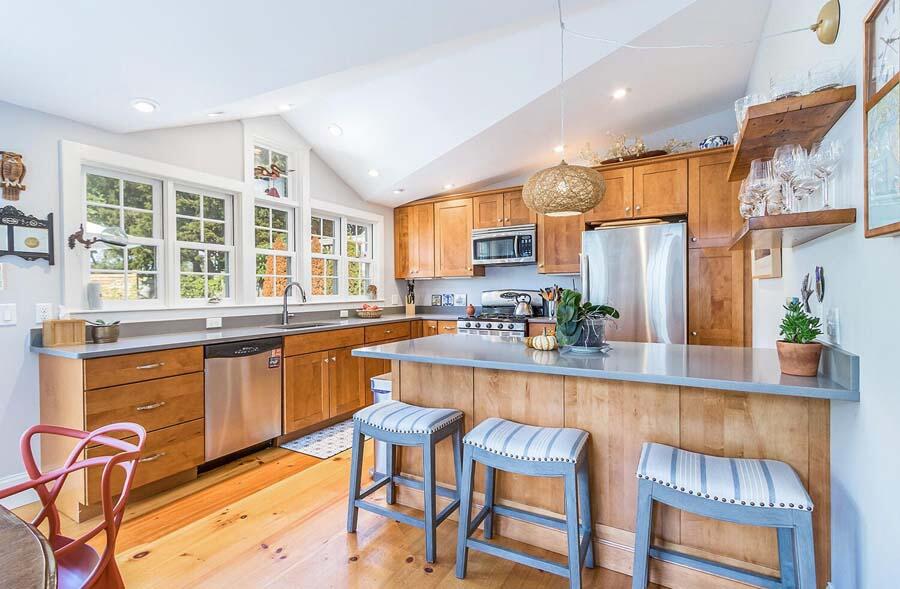 180 Commercial Street Wellfleet, MA 02667 - Photo 4 of 41 a kitchen with stainless steel appliances granite countertop wooden cabinets a dining table and chairs