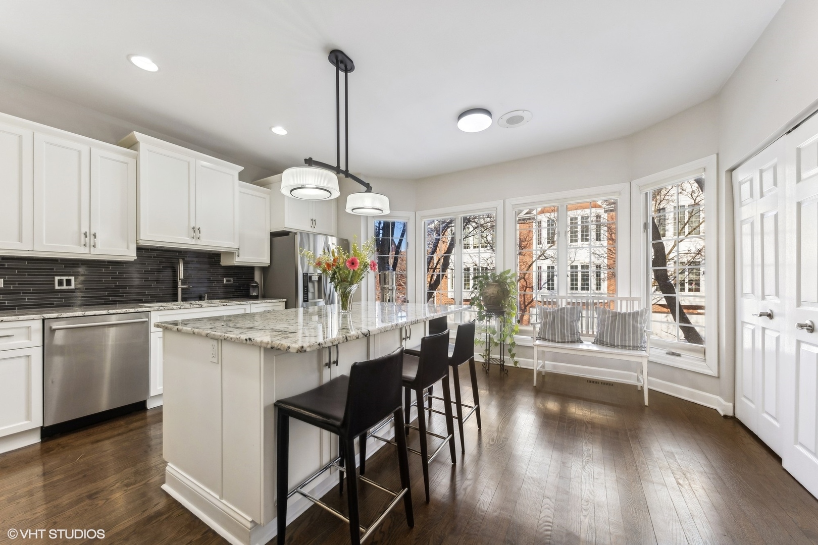 731 South Racine Avenue, Unit B Chicago, IL 60607 - Photo 6 of 29 a kitchen with stainless steel appliances kitchen island granite countertop a stove a sink and white cabinets with wooden floor