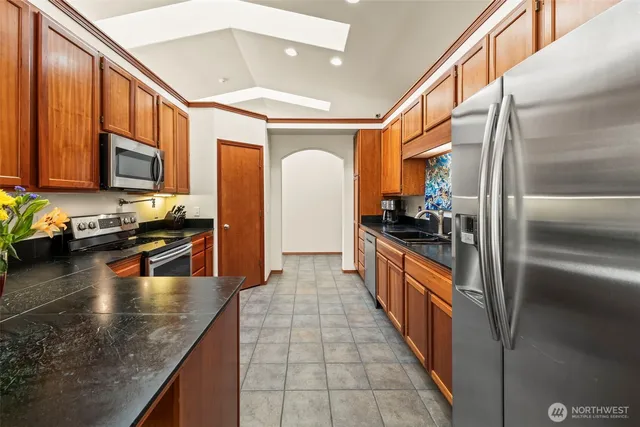 a large kitchen with stainless steel appliances granite countertop a refrigerator a stove and a sink with wooden floor