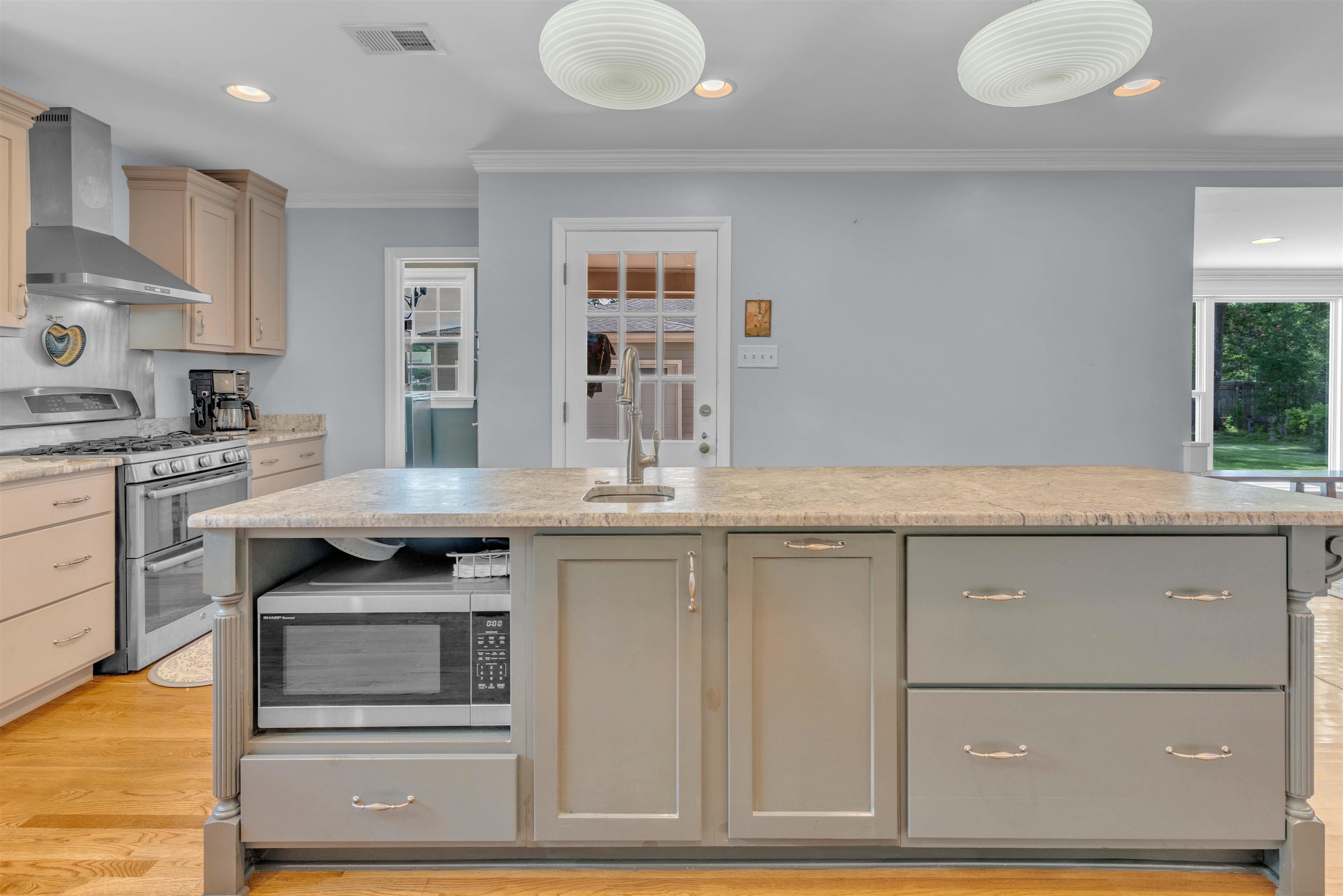 5187 South Angela Road Memphis, TN 38117 - Photo 10 of 39 Kitchen island featuring a built-in microwave, ample cabinet storage, and an integrated sink with a faucet