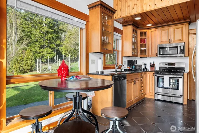 a kitchen with stainless steel appliances kitchen island a table chairs and a sink