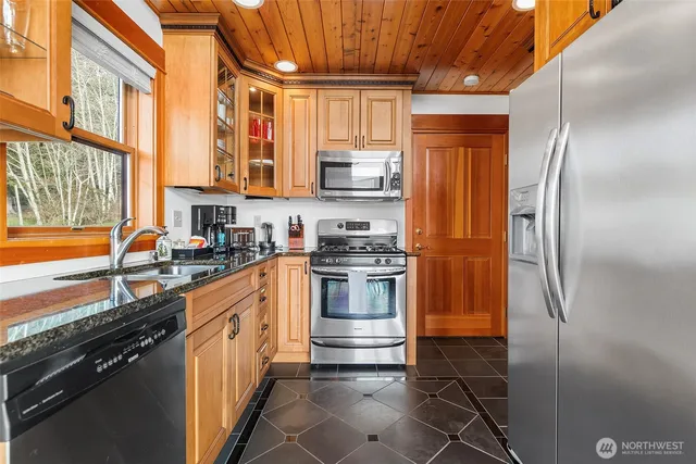 a kitchen with stainless steel appliances granite countertop a refrigerator a sink dishwasher a stove and white countertops with wooden floor