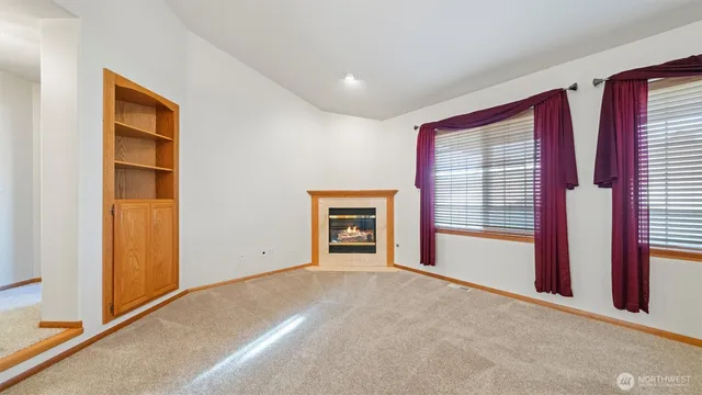 a view of an empty room with a fireplace and a window