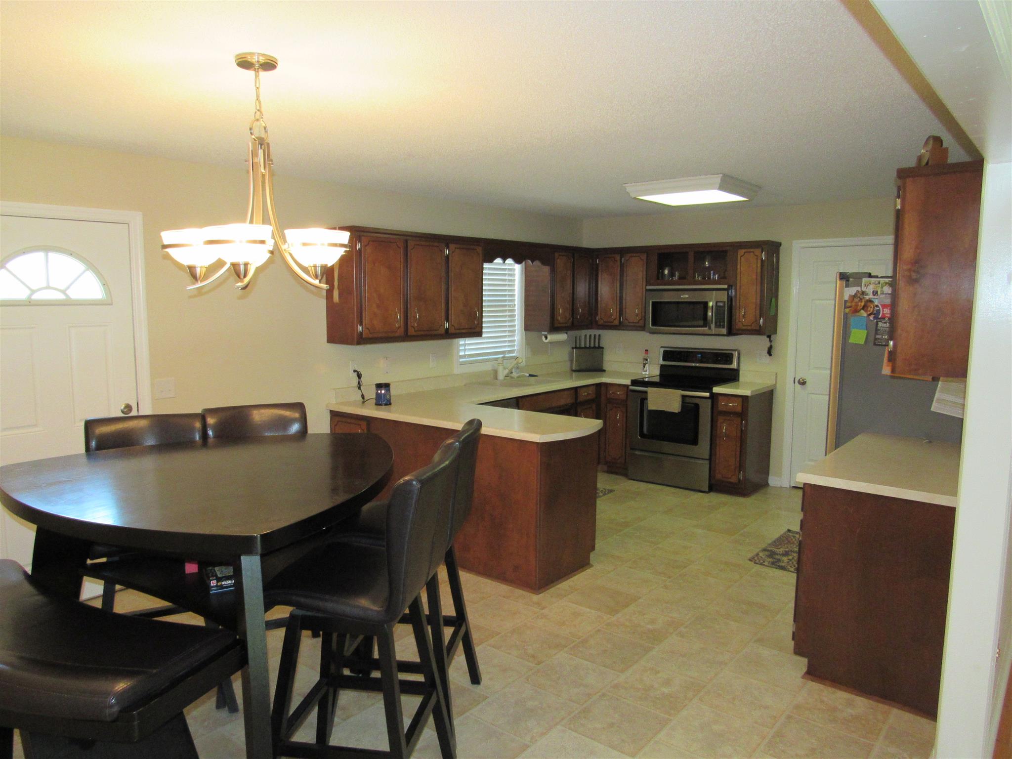 1070 Riley Creek Road Tullahoma, TN 37388 - Photo 8 of 17 a kitchen with stainless steel appliances granite countertop a stove a sink a microwave a dining table and chairs