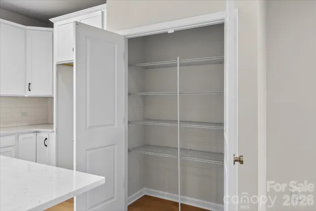 a view of an empty room with wooden floor and windows