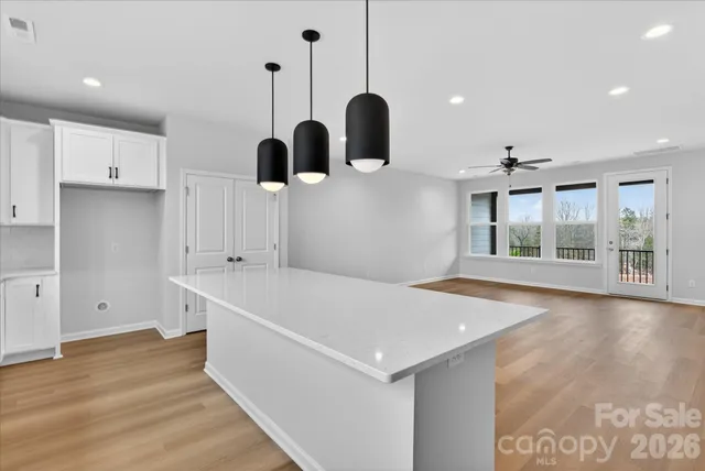 a large kitchen with stainless steel appliances kitchen island a large counter top a stove a sink dishwasher and a refrigerator with wooden floor